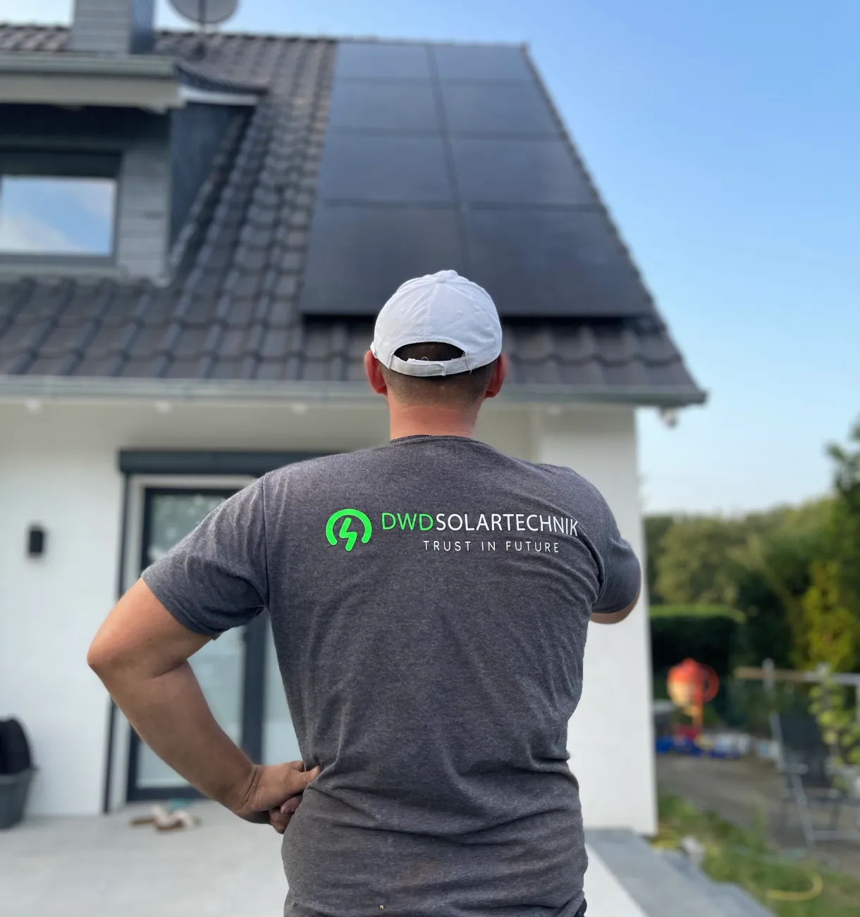 Mitarbeiter von DWD Solartechnik blickt auf ein Einfamilienhaus mit installierter Photovoltaikanlage.